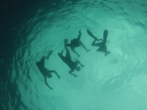 Snorkeling en Méditerranée — quatre nageurs vus sous l'eau, eaux turquoise et lumière diffuse