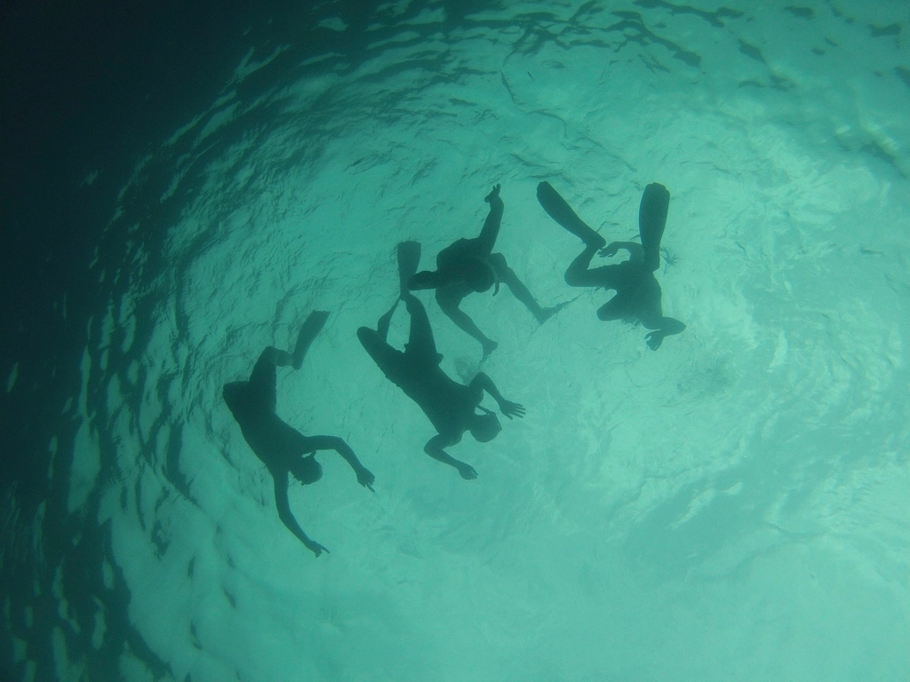 Snorkeling en Méditerranée — quatre nageurs vus sous l'eau, eaux turquoise et lumière diffuse