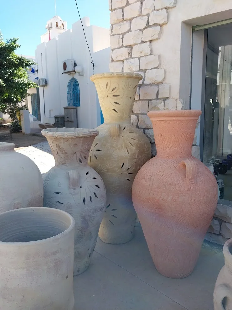 Grandes jarres décoratives sculptées exposées devant une boutique de Guellala, Djerba