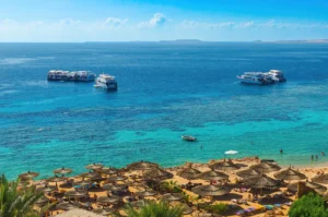 Plage de Sharm el-Sheikh, baie de Ras Um Sid — eau turquoise mer Rouge, bateaux et parasols