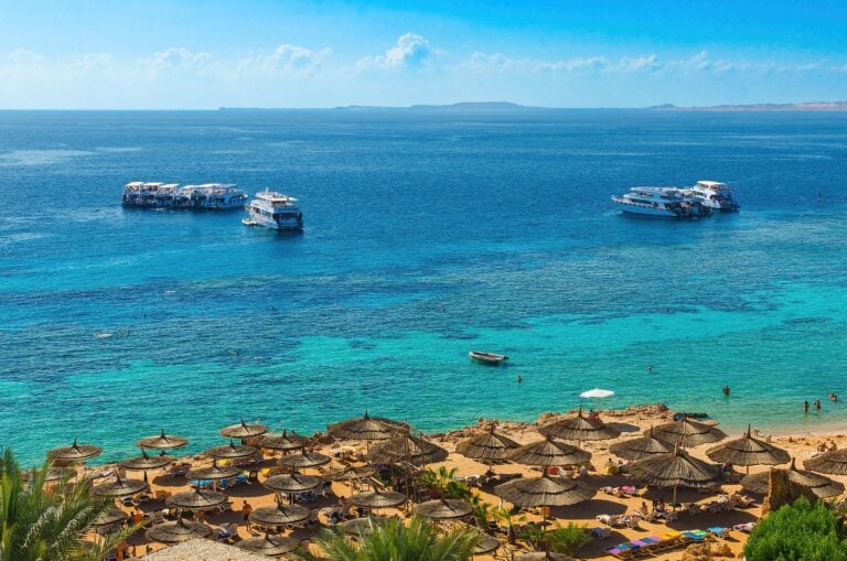 Plage de Sharm el-Sheikh, baie de Ras Um Sid — eau turquoise mer Rouge, bateaux et parasols