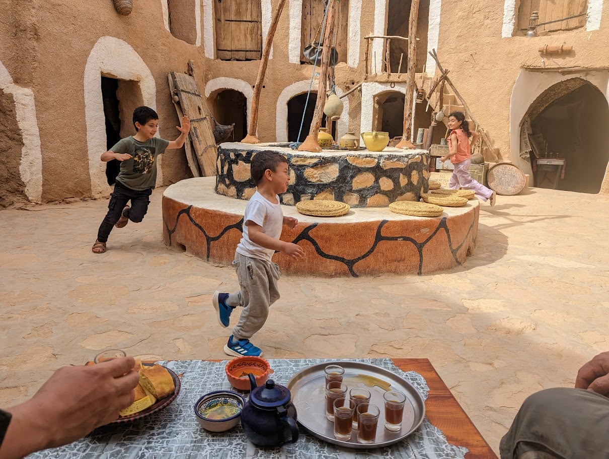 Enfants jouant dans une cour troglodyte de Matmata, thé à la menthe au premier plan