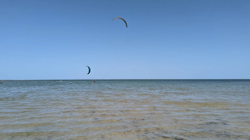 Flaches, klares Meer mit Kitesurfern an der Südostküste von Djerba bei Sedouikech