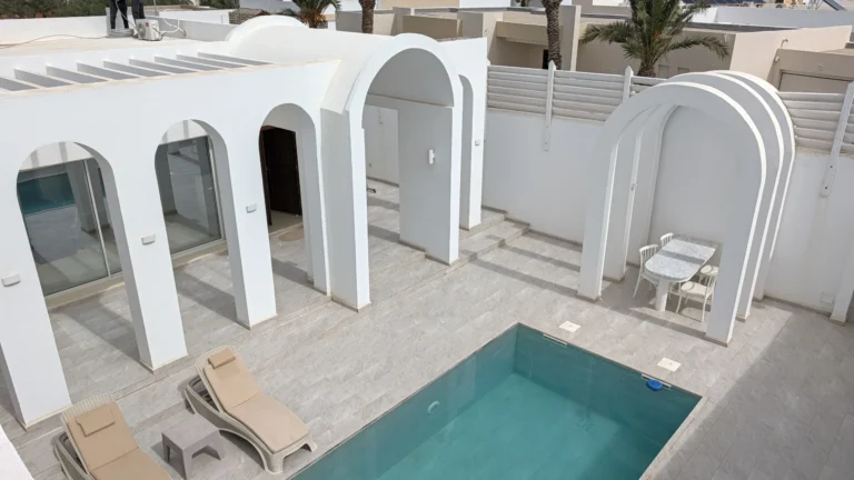 Aerial view of Villa Jade's pool with sun loungers and white arches