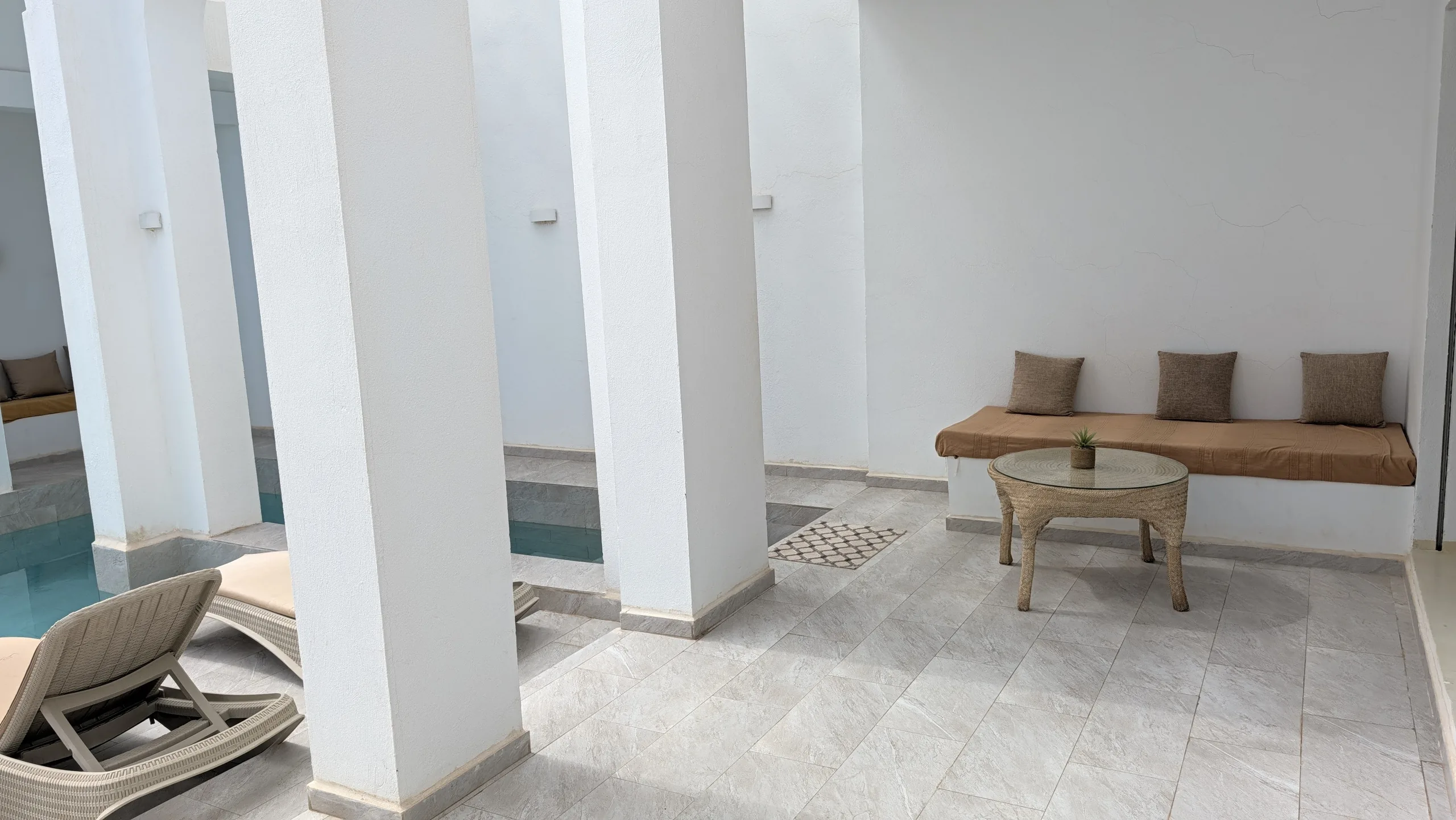 Villa Jade a Djerba: patio bianco con archi, panca in muratura, lettini e vasca stretta non visibile dai vicini