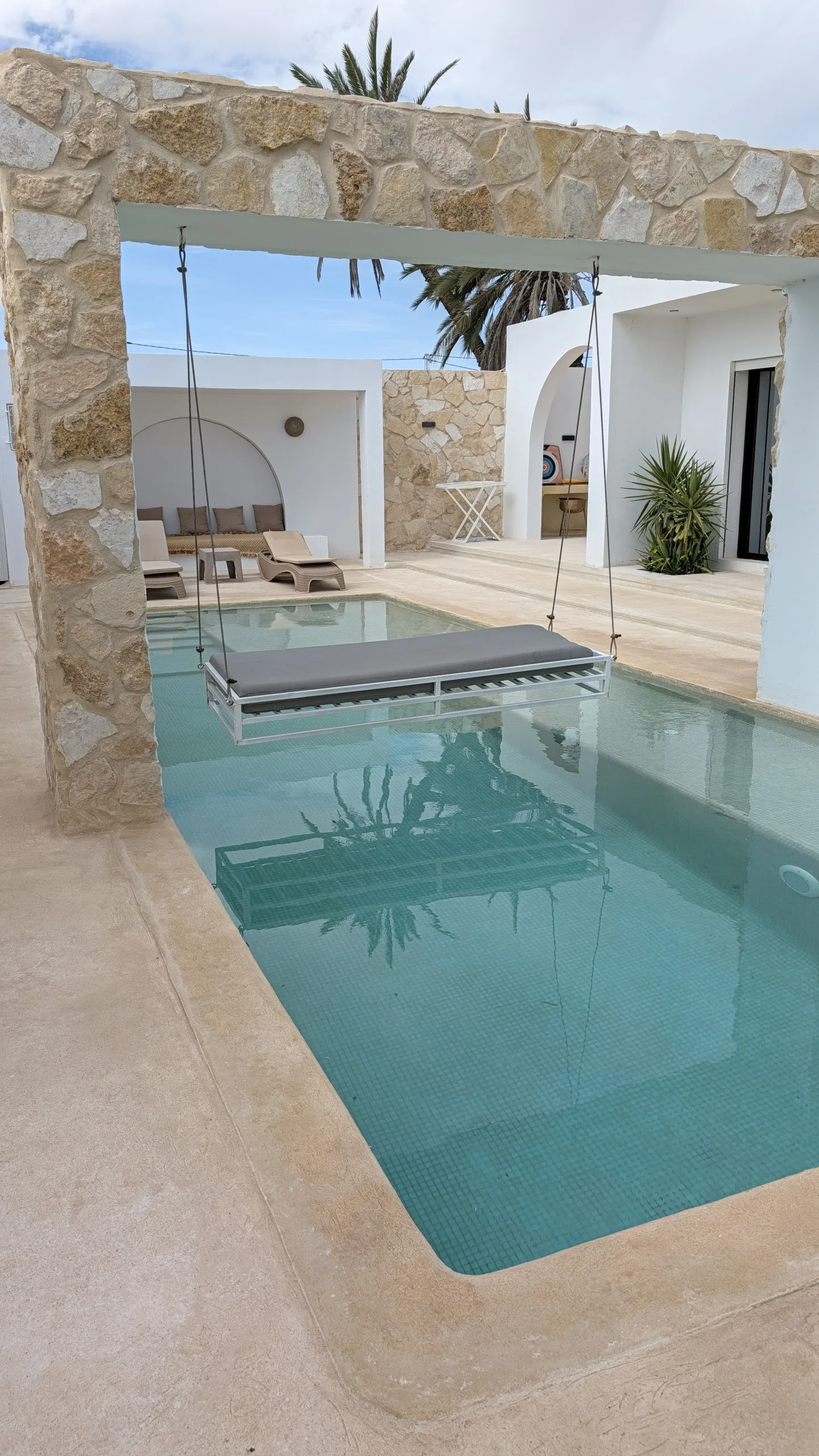 Villa Opale a Djerba a novembre: piscina privata sotto un portico in pietra, altalena sospesa e palme